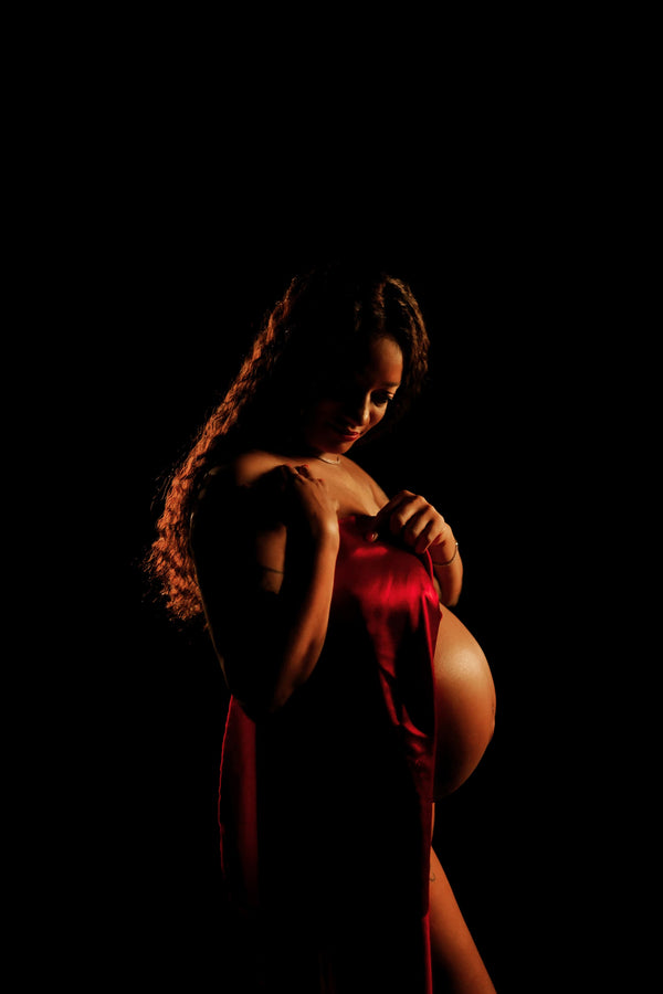 Pregnant individual posing for Nuovo’s Life collection on a black backdrop
